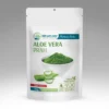 Aloe vera prah u beloj kesici sa zelenim prahom i presecima lista aloe vere